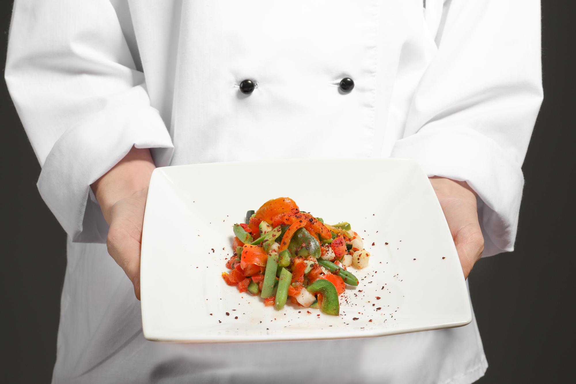 Chef demonstrating plating in a calm kitchen